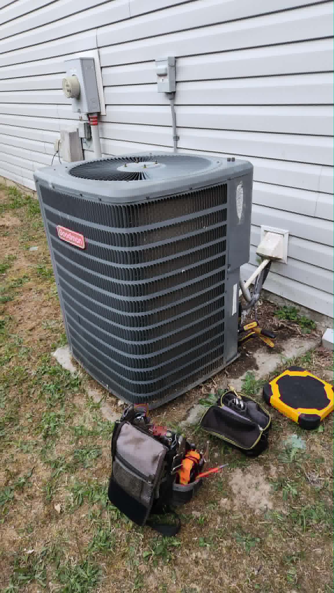 Technician's tools beside a Goodman condenser during a service call